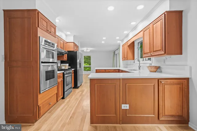 a kitchen with stainless steel appliances granite countertop wooden cabinets a sink and dishwasher with wooden floor