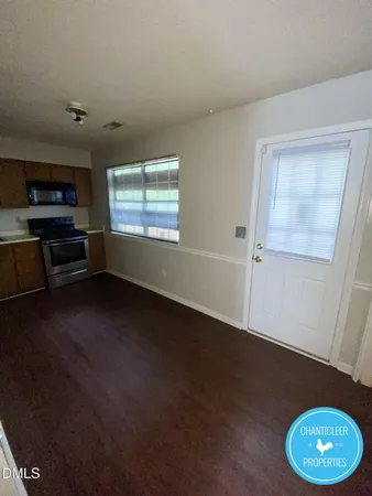a view of an empty room with a window and wooden floor