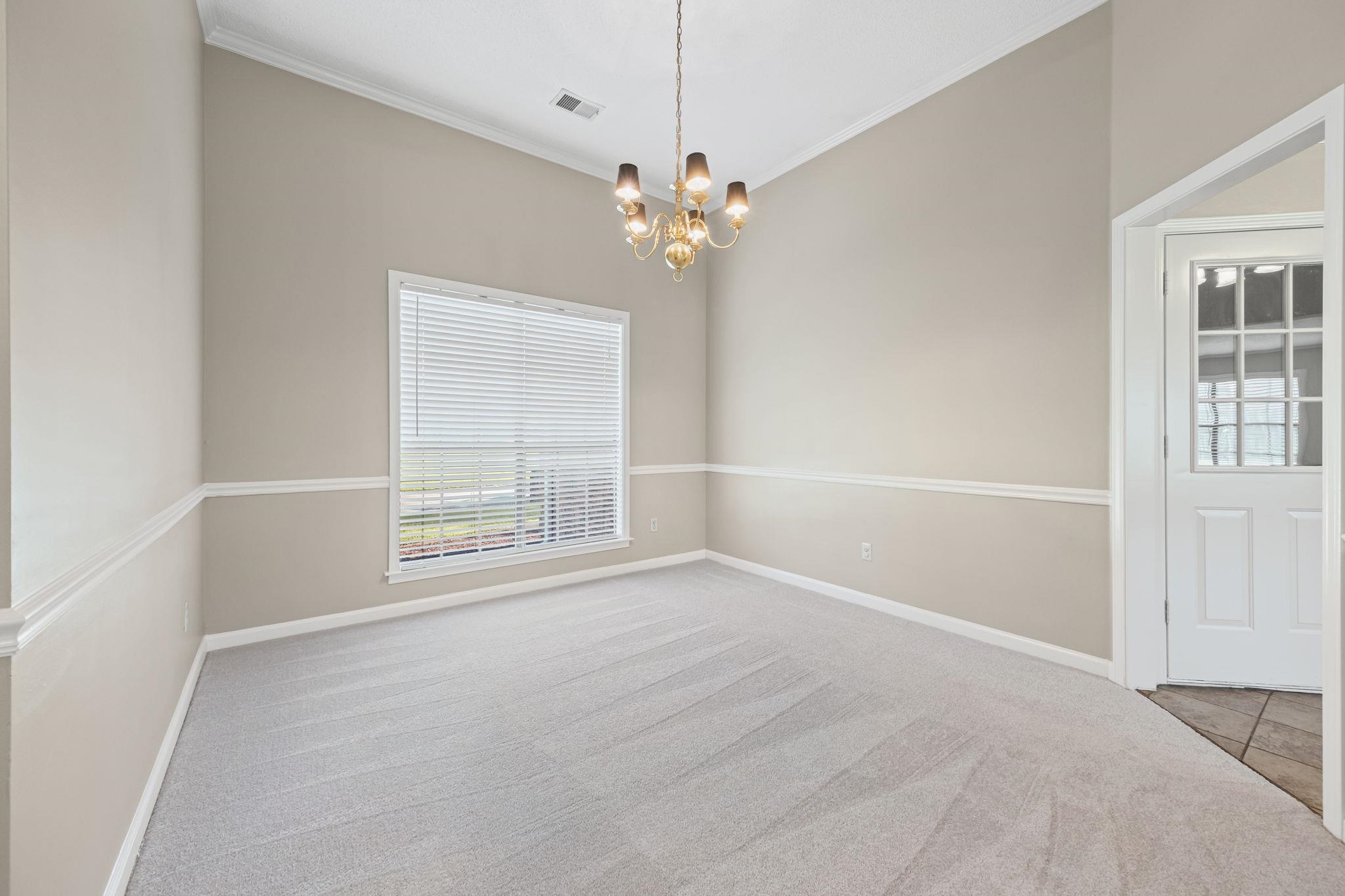 8409 Ridge Fall Cove Memphis, TN 38018 - Photo 10 of 28 Carpeted spare room with a chandelier and ornamental molding