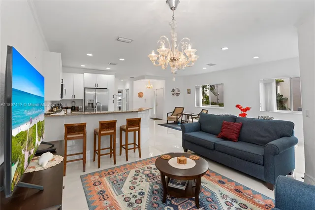 a living room with stainless steel appliances kitchen island granite countertop furniture and a rug