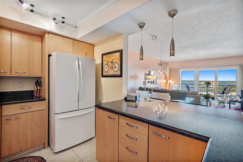 a kitchen with granite countertop a refrigerator a sink a center island and furniture