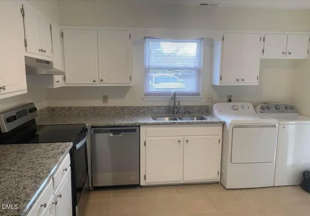 a kitchen with granite countertop white cabinets sink and stainless steel appliances
