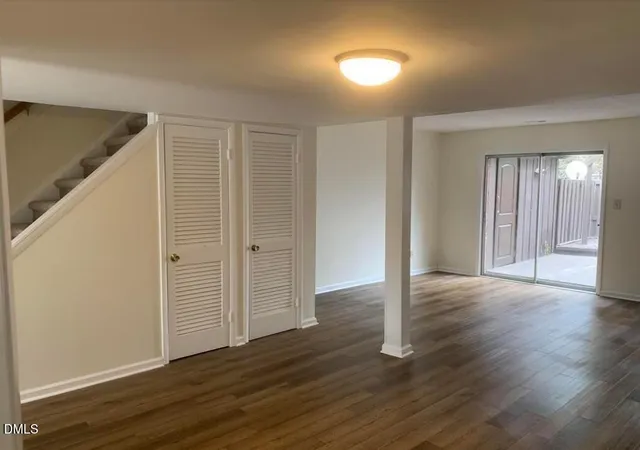 an empty room with wooden floor & windows