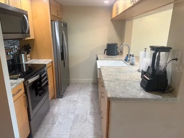 a kitchen with stainless steel appliances granite countertop a refrigerator and a stove