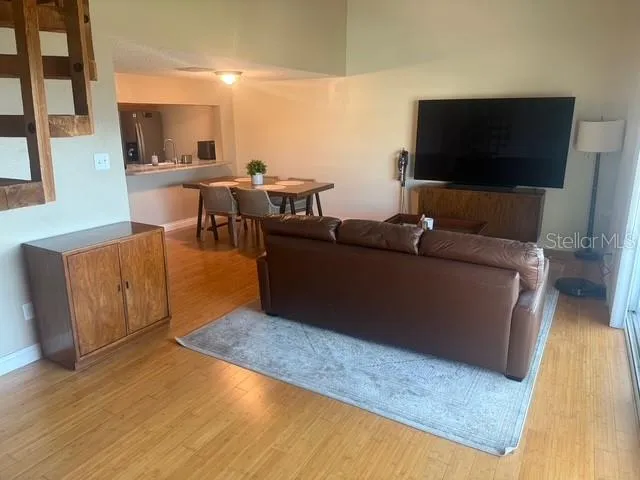 a living room with couches and a flat screen tv with kitchen view
