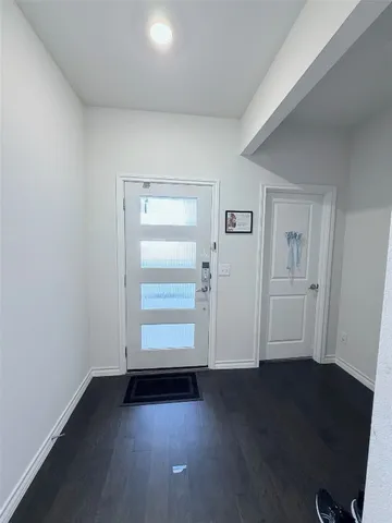 an empty room with wooden floor cabinet and windows