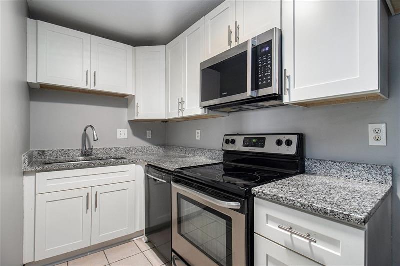 3599 Woodbriar Circle, Unit A Tucker, GA 30084 - Photo 13 of 30 a kitchen with granite countertop white cabinets and a stove top oven