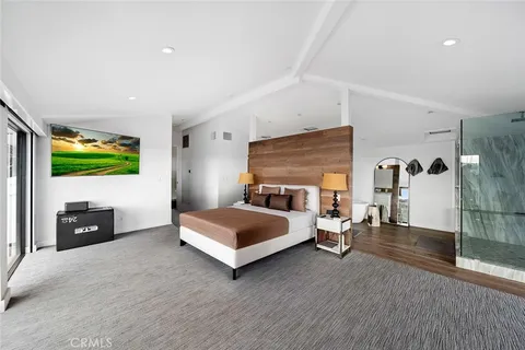 a bedroom with a bed and a flat tv screen on dresser