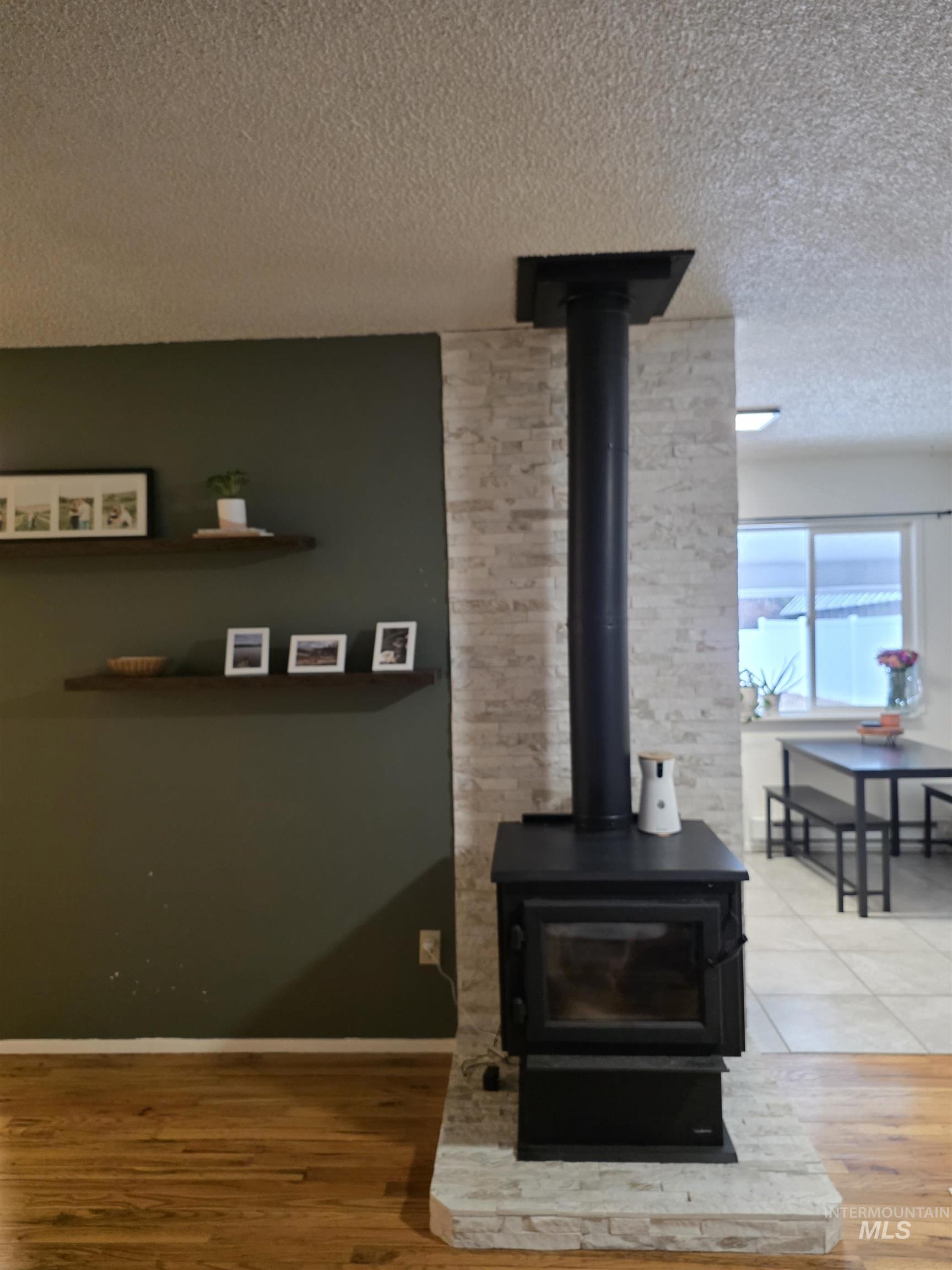 179 Timberline Drive Pierce, ID 83546 - Photo 11 of 24 Detailed view of a wood stove, a textured ceiling, and wood finished floors