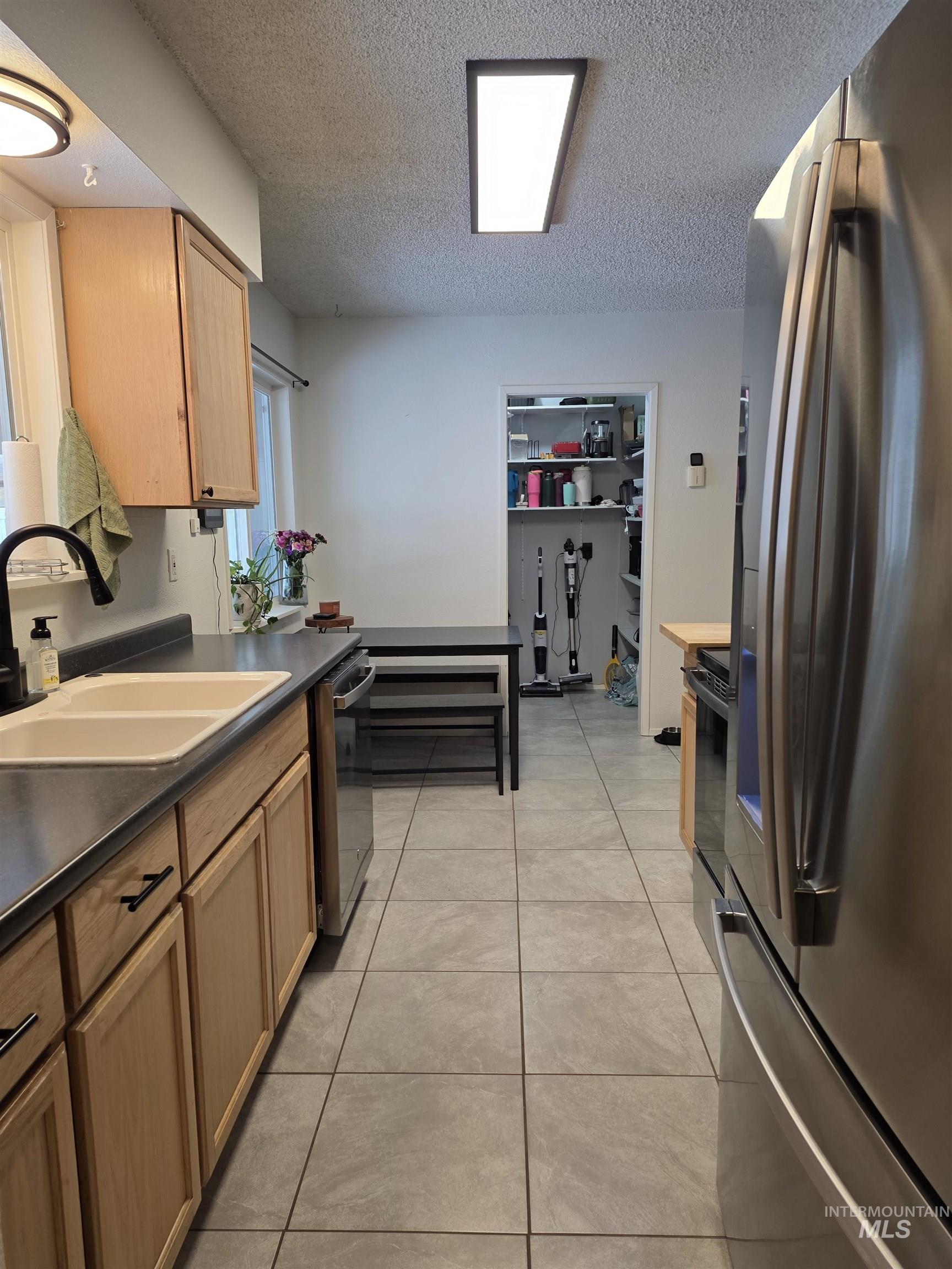 179 Timberline Drive Pierce, ID 83546 - Photo 13 of 24 Kitchen with dark countertops, stainless steel appliances, a textured ceiling, and light tile patterned flooring