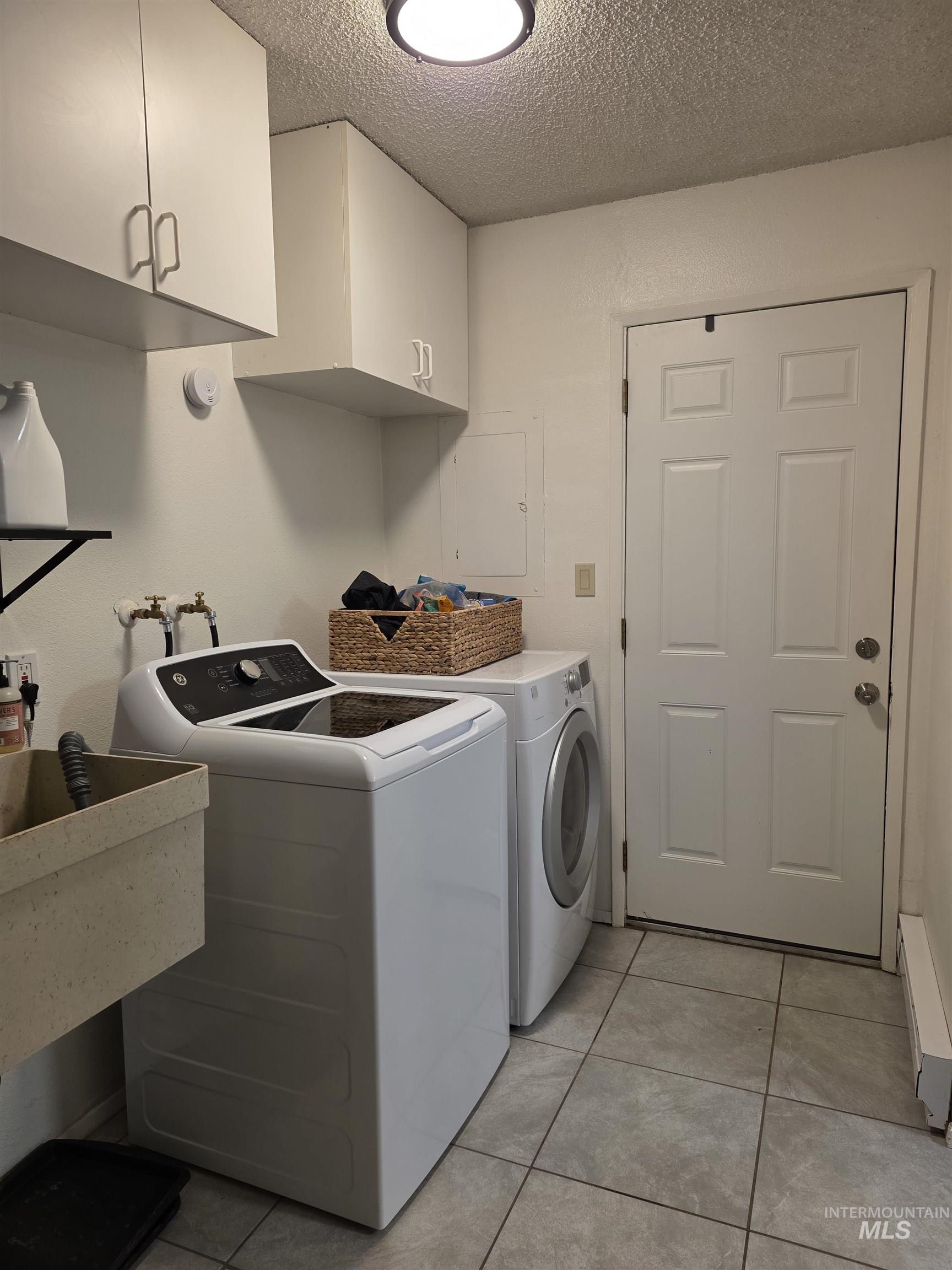 179 Timberline Drive Pierce, ID 83546 - Photo 18 of 24 Laundry room with cabinet space, a textured ceiling, light tile patterned flooring, washing machine and dryer, and electric panel