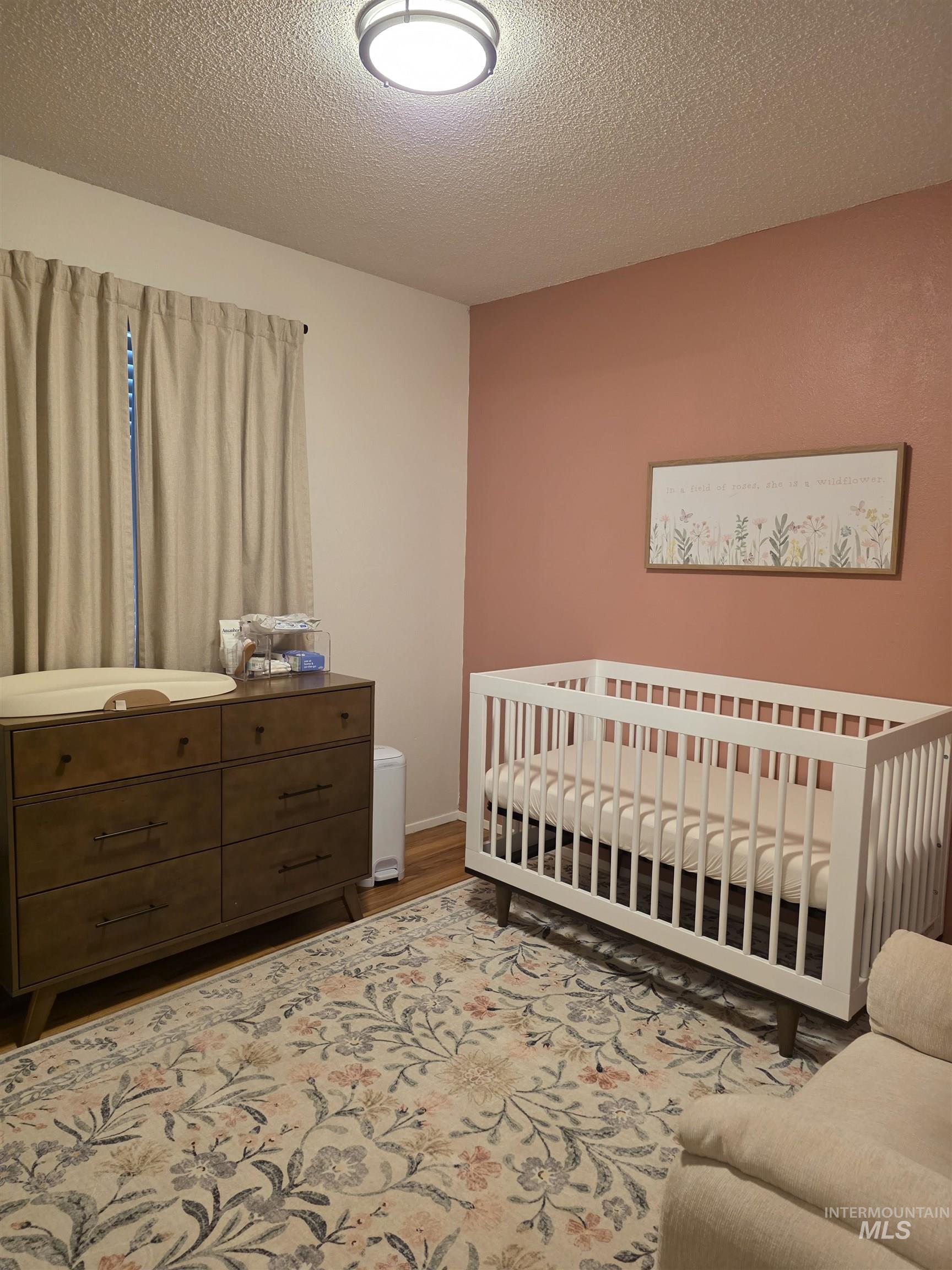 179 Timberline Drive Pierce, ID 83546 - Photo 24 of 24 Bedroom with a crib, a textured ceiling, and wood finished floors