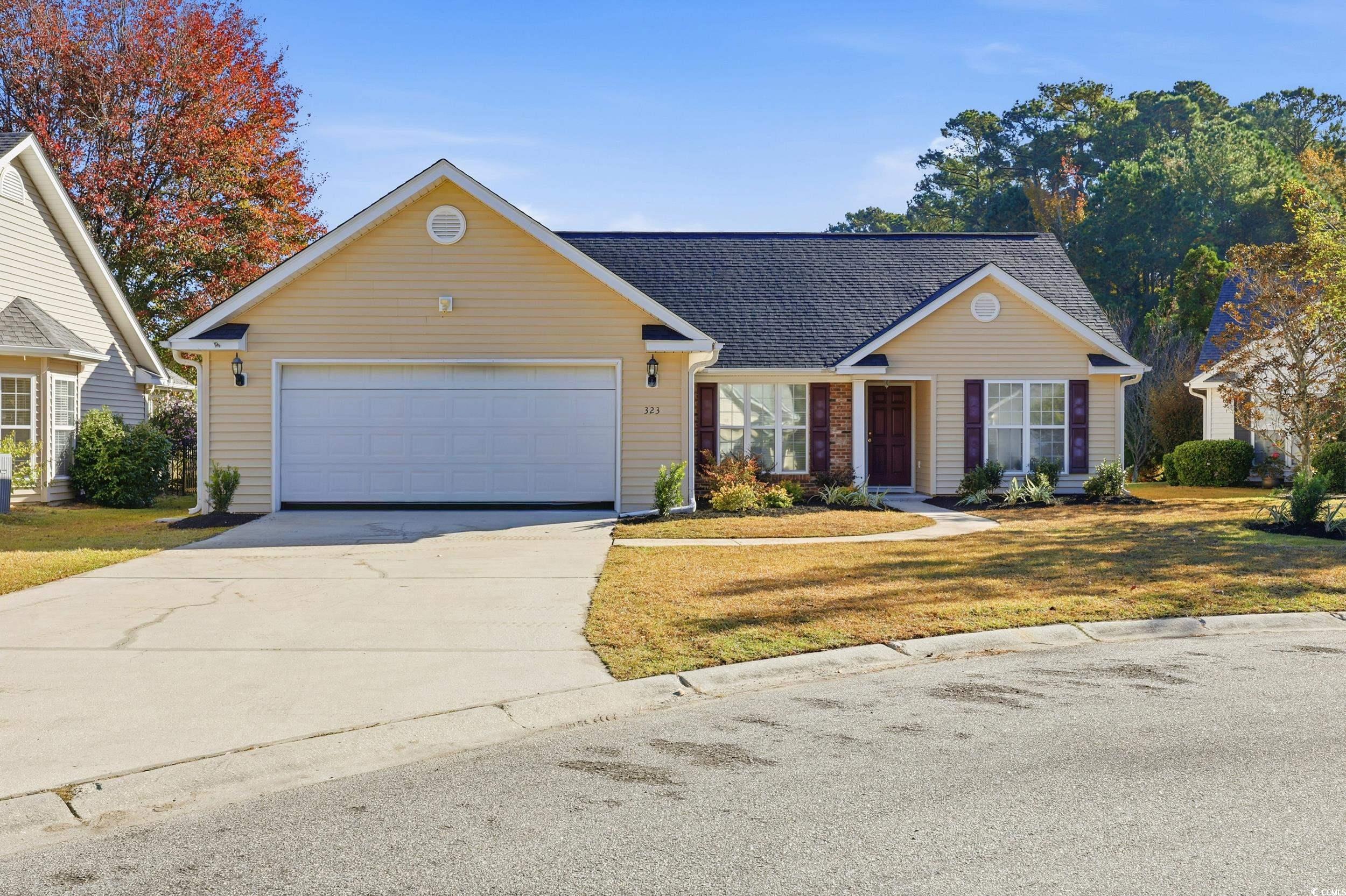 View of front of property featuring driveway, roof with shingles, a front yard, and a garage