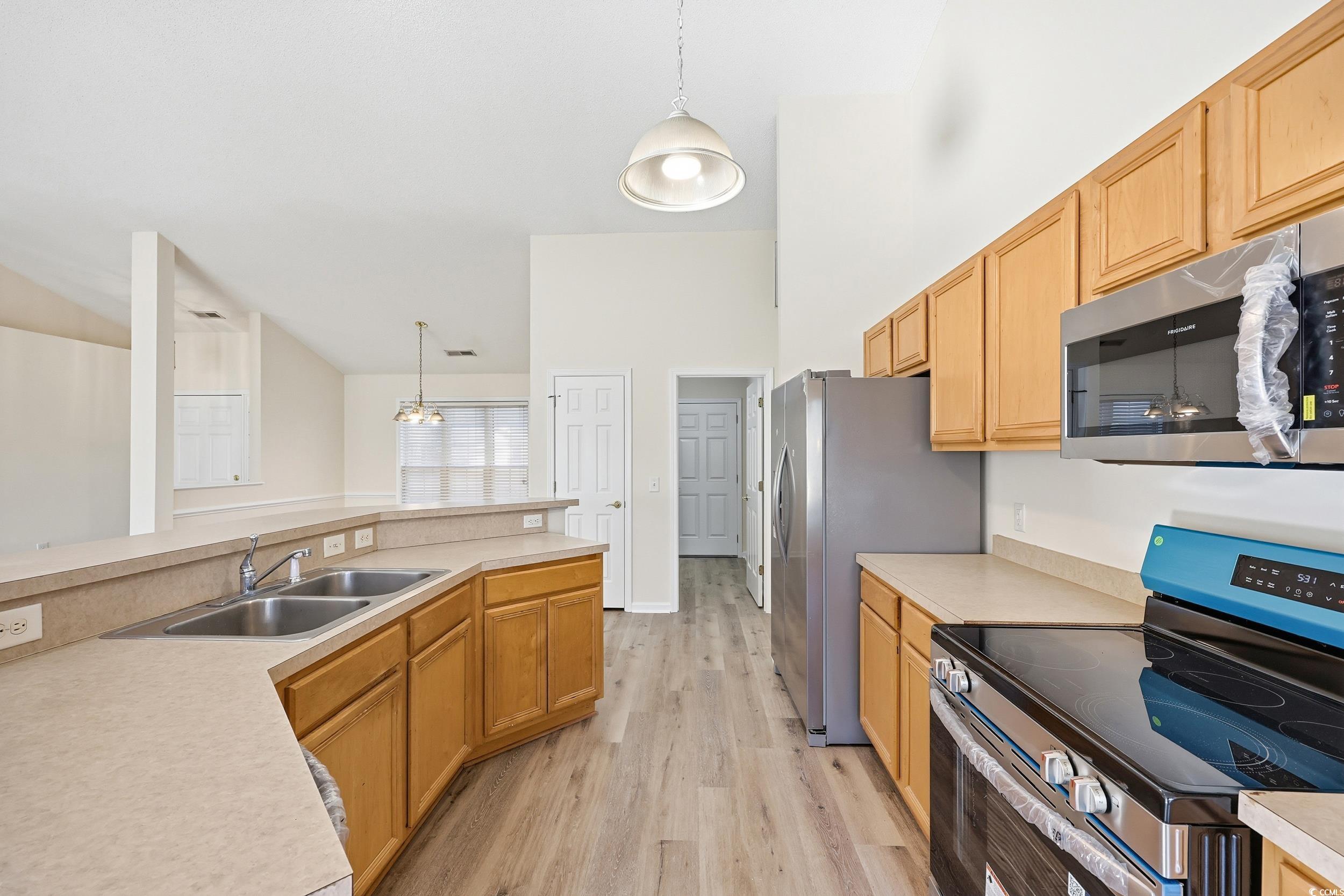 323 Chastain Court Murrells Inlet, SC 29576 - Photo 12 of 37 Kitchen with appliances with stainless steel finishes, hanging light fixtures, light wood-style flooring, light countertops, and vaulted ceiling
