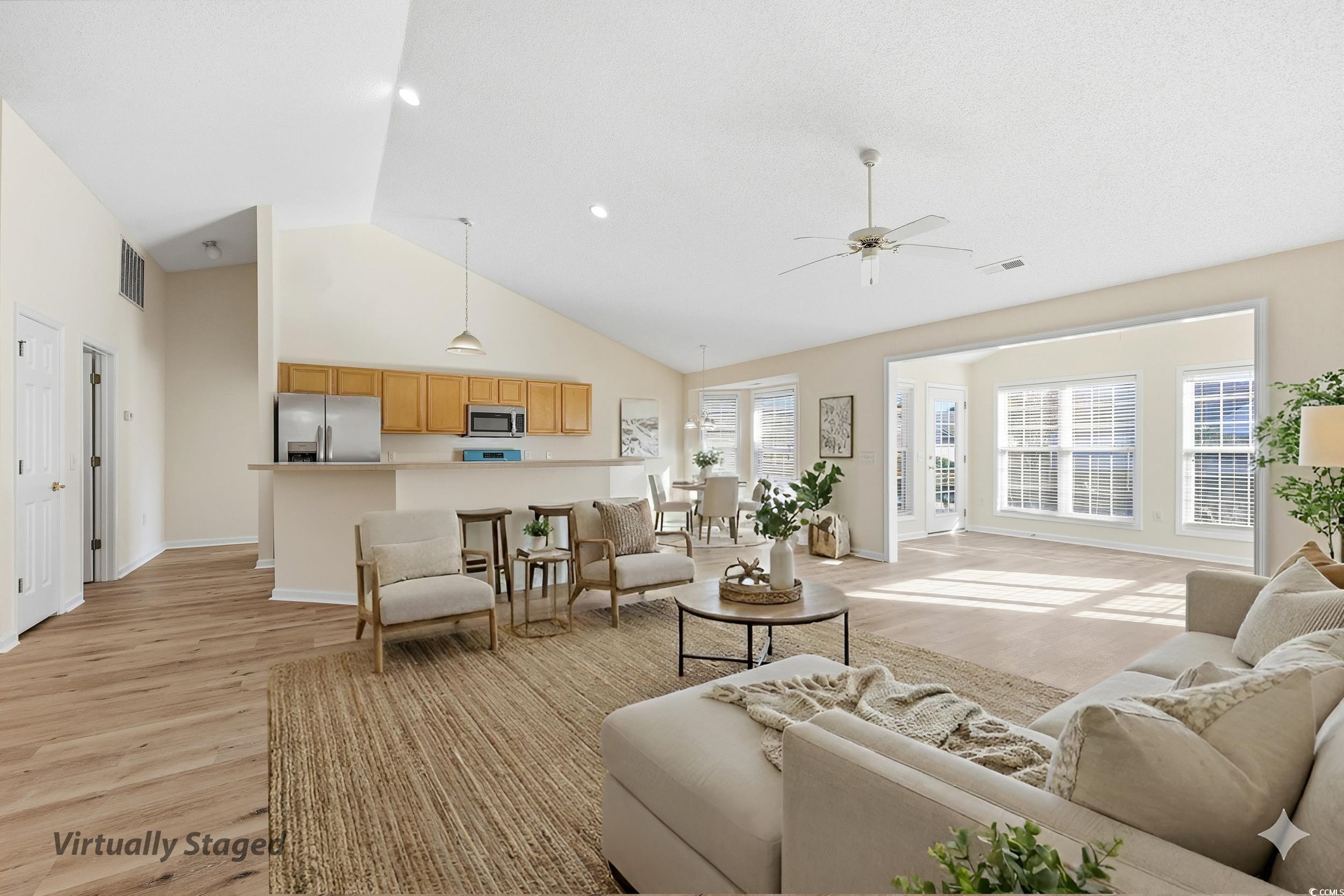 Living area featuring high vaulted ceiling, a ceiling fan, and light wood finished floors