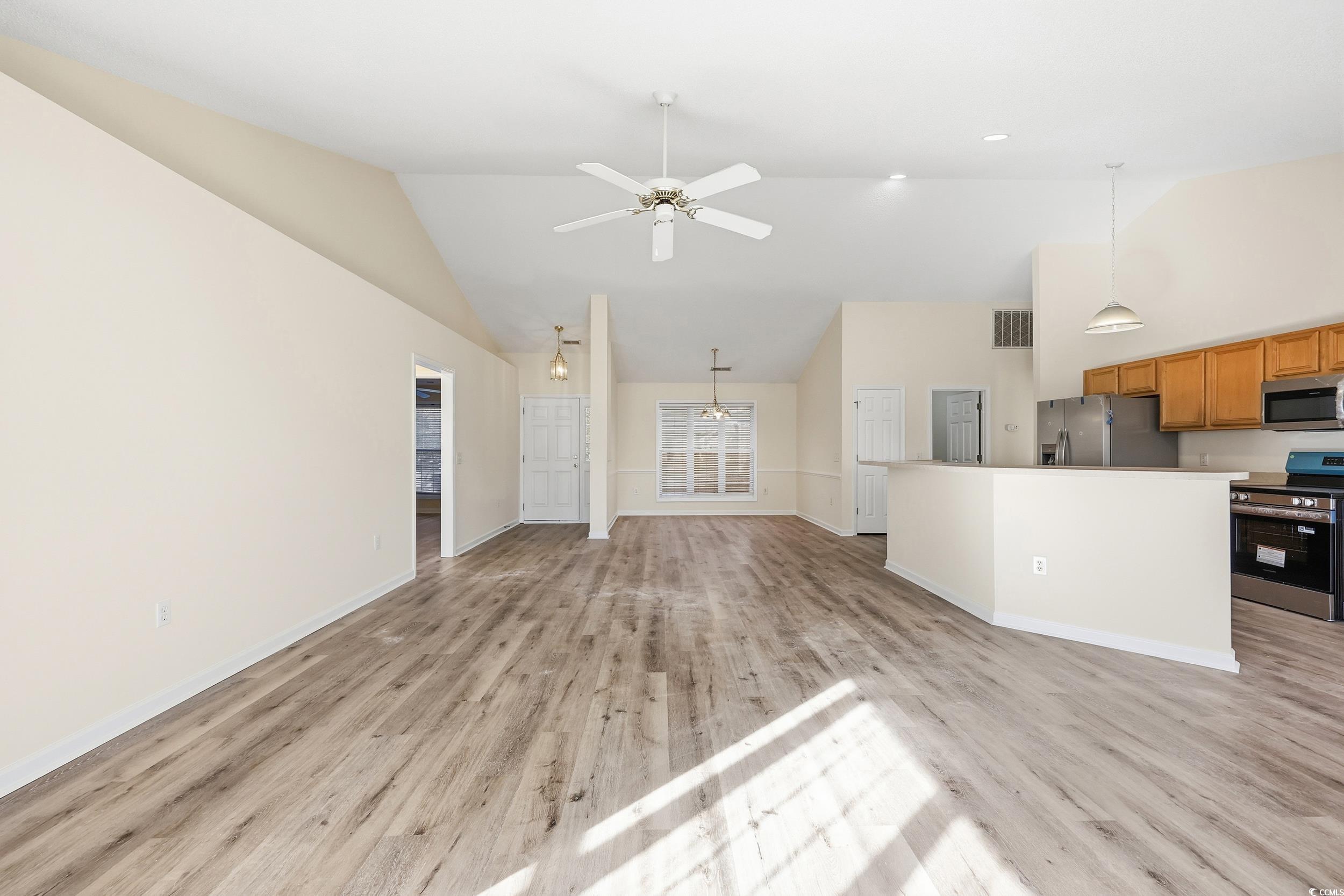 Unfurnished living room featuring light wood-style flooring, high vaulted ceiling, and a ceiling fan