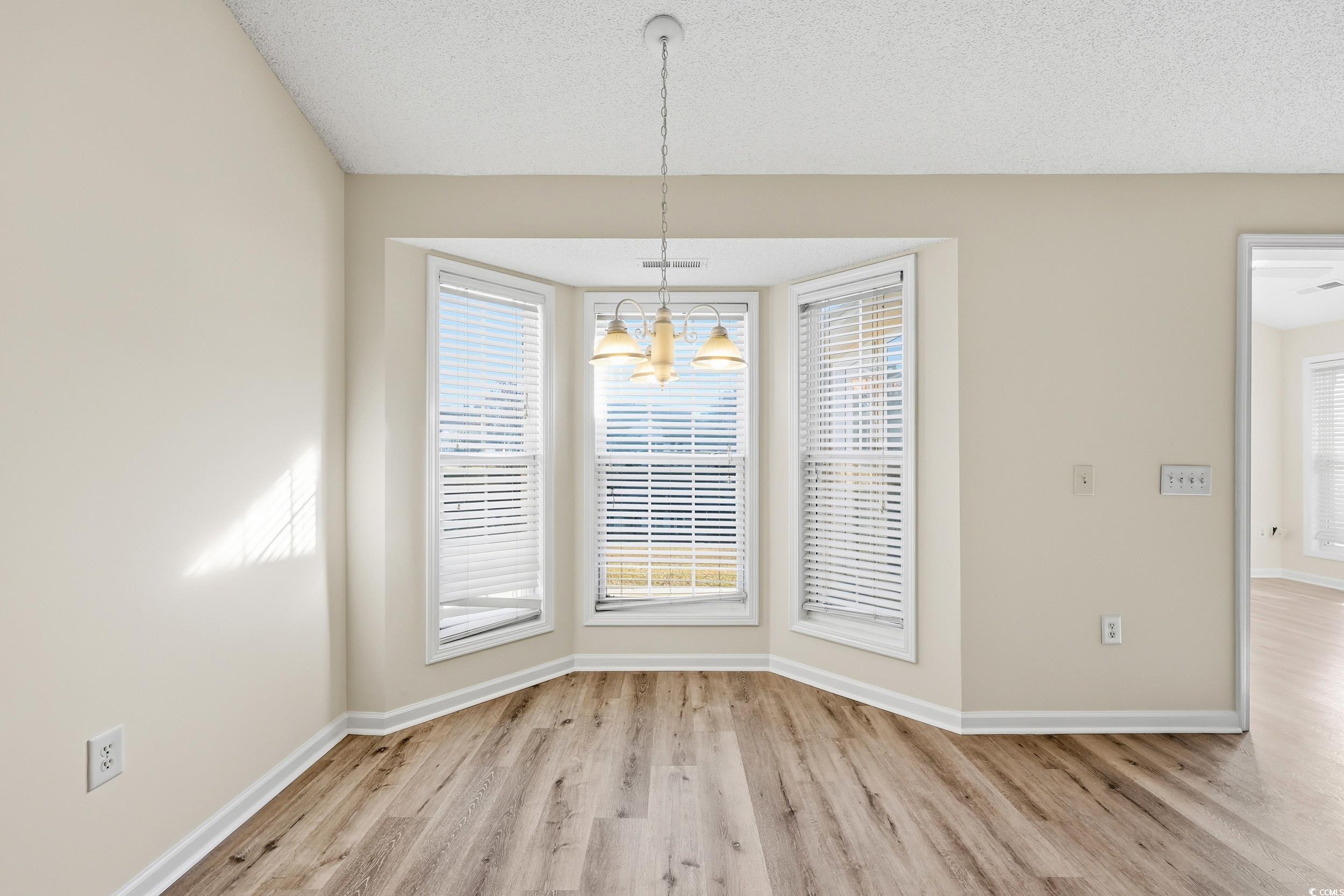 323 Chastain Court Murrells Inlet, SC 29576 - Photo 9 of 37 Unfurnished living room featuring light wood-type flooring, a chandelier, high vaulted ceiling, a ceiling fan, and a textured ceiling