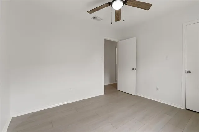 an empty room with wooden floor ceiling fan and windows