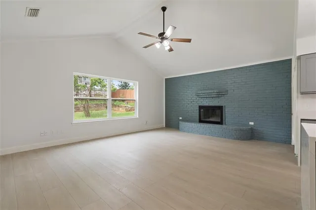 an empty room with wooden floor chandelier fan and windows