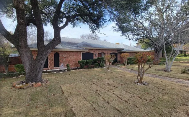 a view of a house with large tree and wooden fence