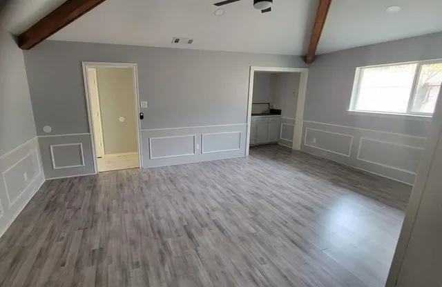 an empty room with wooden floor and windows