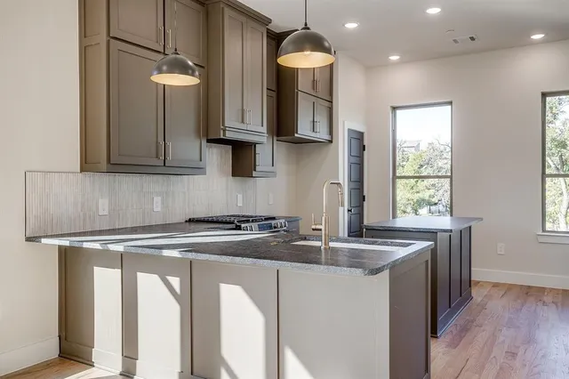 a kitchen with granite countertop a sink a stove and cabinets