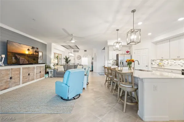 a living room with furniture a flat screen tv and kitchen view