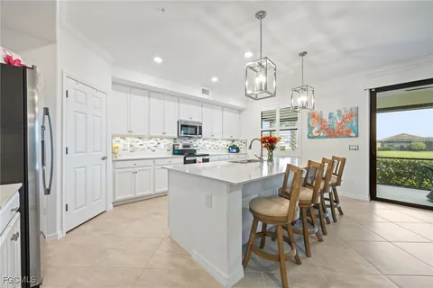 a kitchen with stainless steel appliances kitchen island granite countertop a table chairs and a refrigerator
