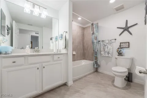 a bathroom with a toilet a sink a mirror a bathtub and vanity