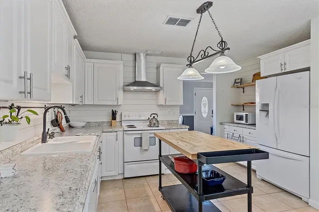 a kitchen with stainless steel appliances granite countertop a sink a stove a refrigerator and center island