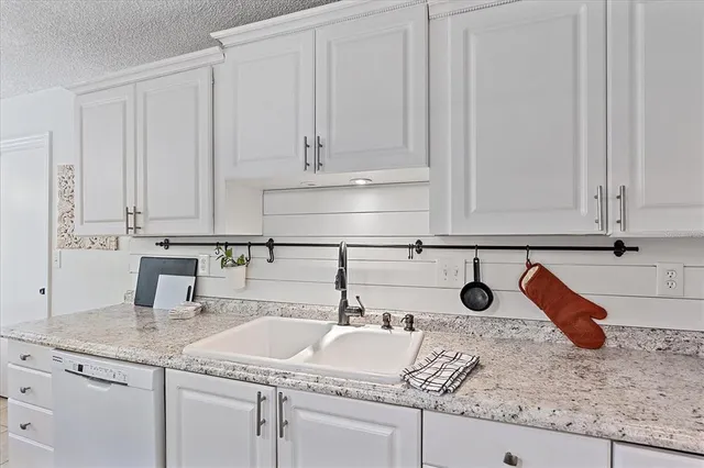 a kitchen with granite countertop white cabinets and a sink