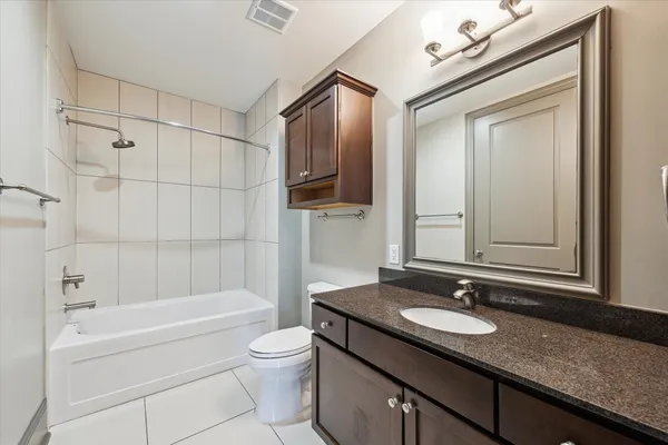 a bathroom with a granite countertop sink vanity mirror bathtub shower and a mirror