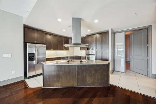 a view of a kitchen with stainless steel appliances granite countertop a stove a refrigerator and a sink with wooden floor