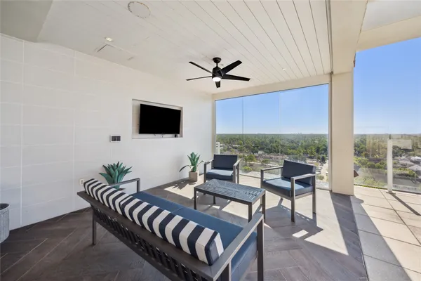 a living room with furniture a flat screen tv and a floor to ceiling window