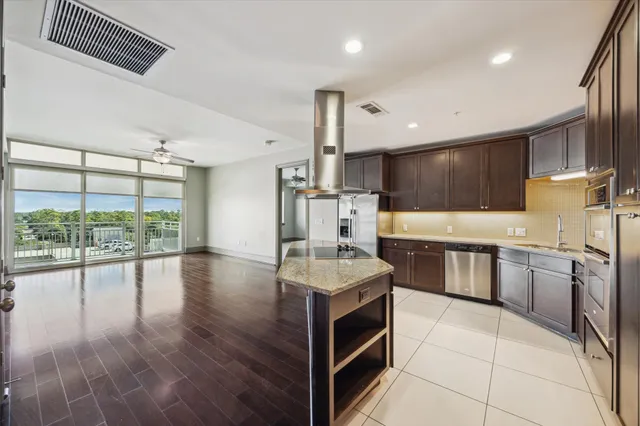 a large kitchen with stainless steel appliances a large counter top a stove and a wooden floors