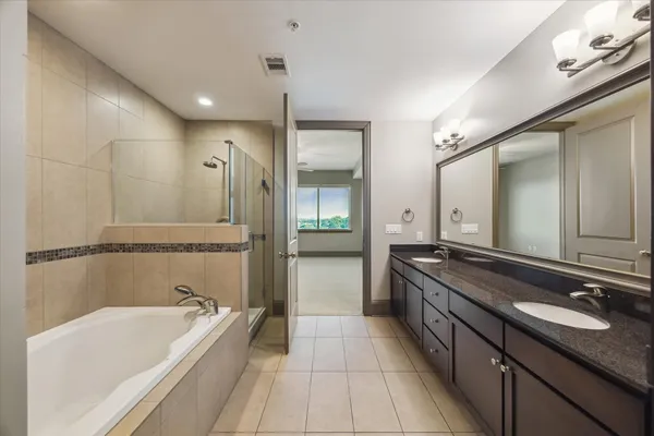 a bathroom with a granite countertop double vanity sink and mirror with bathtub