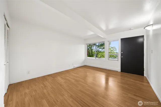 a view of an empty room with wooden floor and a window