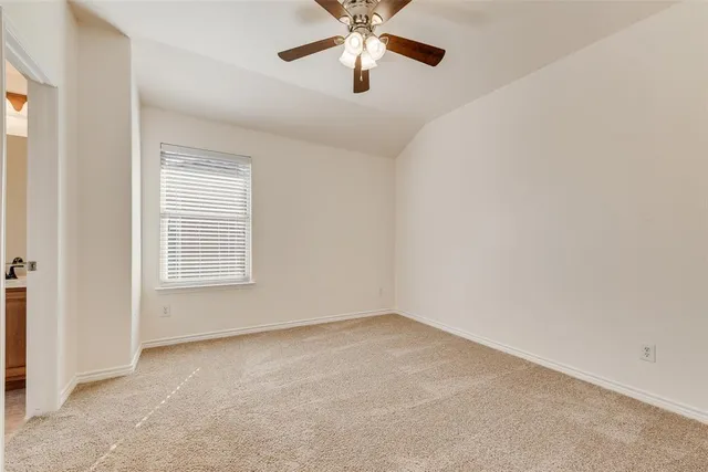 an empty room with chandelier fan and windows