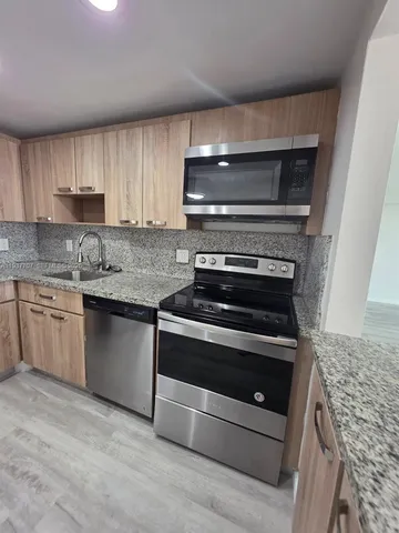 a kitchen with granite countertop a stove and a sink