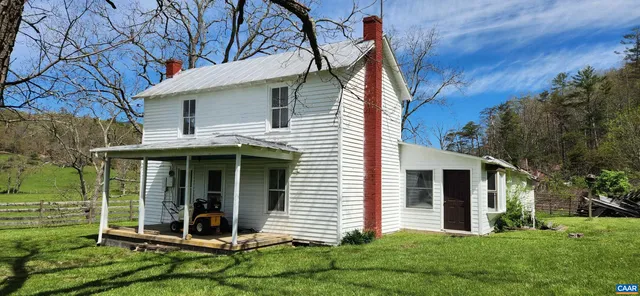a view of a white house with a yard and large tree