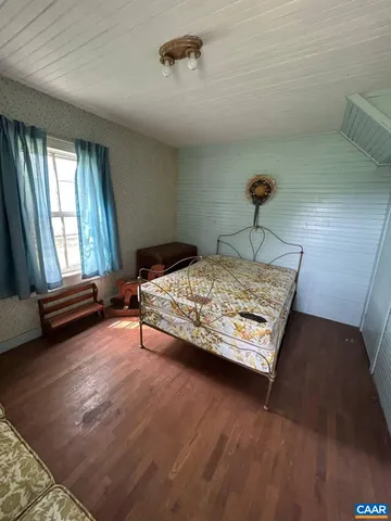a bedroom with a bed windows and wooden floor