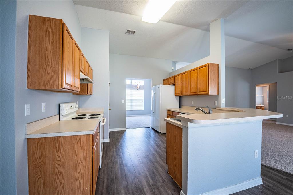 233 Towhee Road Winter Haven, FL 33881 - Photo 21 of 87 a kitchen with stainless steel appliances granite countertop a stove top oven a sink dishwasher and a microwave oven with wooden floor