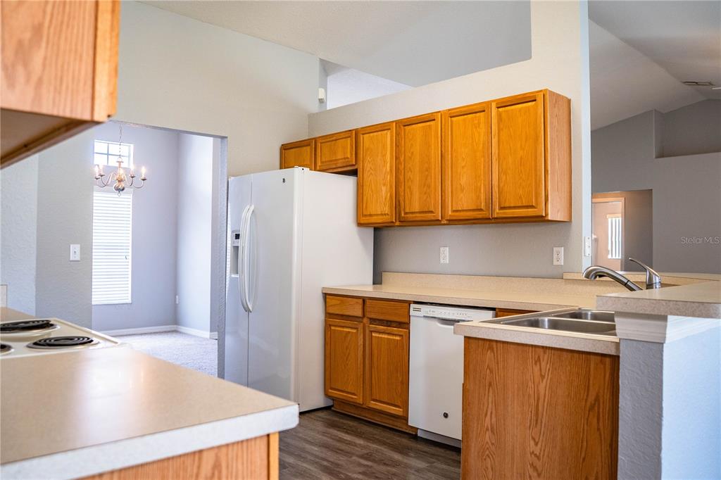 233 Towhee Road Winter Haven, FL 33881 - Photo 22 of 87 a kitchen with stainless steel appliances granite countertop a refrigerator a sink dishwasher and white cabinets with wooden floor