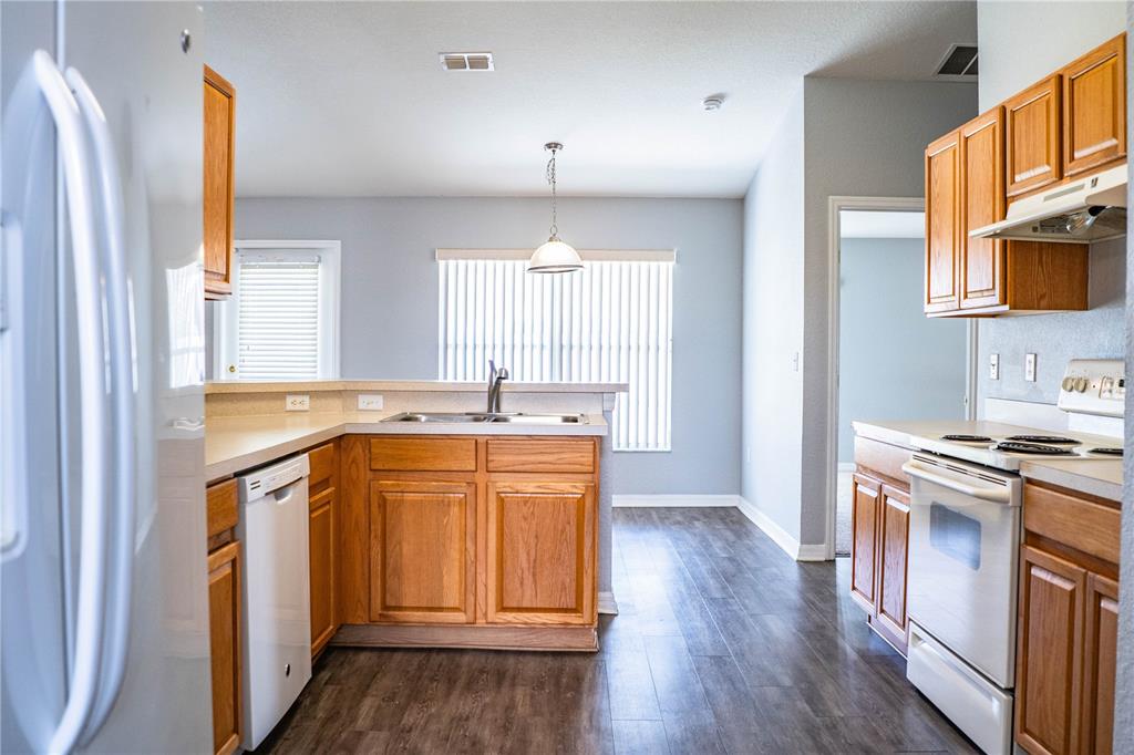 233 Towhee Road Winter Haven, FL 33881 - Photo 26 of 87 a kitchen with stainless steel appliances granite countertop a stove a sink and a refrigerator with wooden floors