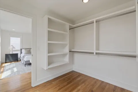 a view of an empty room with wooden floor and a closet