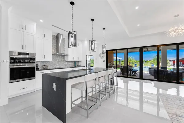 a large kitchen with kitchen island a large counter top space a sink stainless steel appliances and cabinets
