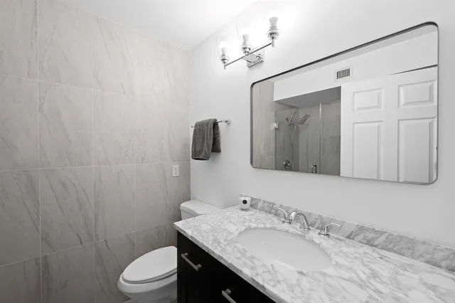 a bathroom with a granite countertop sink toilet and mirror