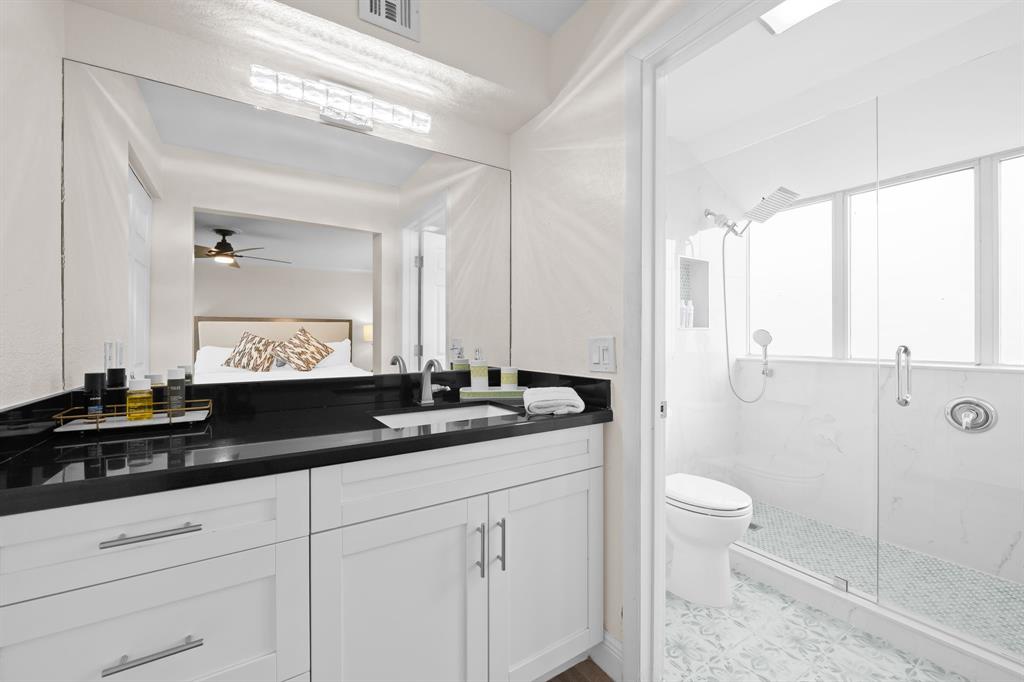 5298 Buckhead Circle, Unit 1040 Boca Raton, FL 33431 - Photo 19 of 25 a bathroom with a granite countertop sink a toilet a mirror and shower