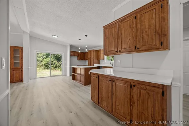 a kitchen with stainless steel appliances granite countertop a refrigerator a sink dishwasher and wooden cabinets with wooden floor