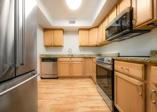 a kitchen with stainless steel appliances granite countertop a stove a sink and a refrigerator